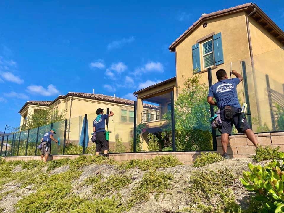 Bright N Shiny crew cleaning glass railings at a home
